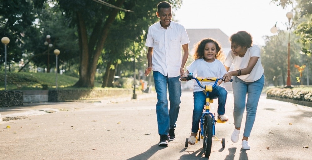 Couple teaching her daugther how to ride a bike